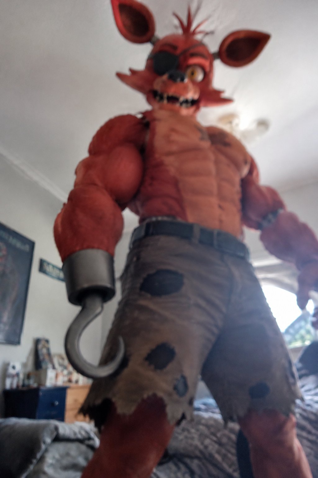 Costumed red animatronic character standing indoors, photographed from a low angle.